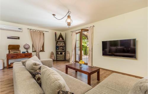 a living room with a couch and a tv on a wall at 3 Bedroom Cozy Home In Palit in Palit