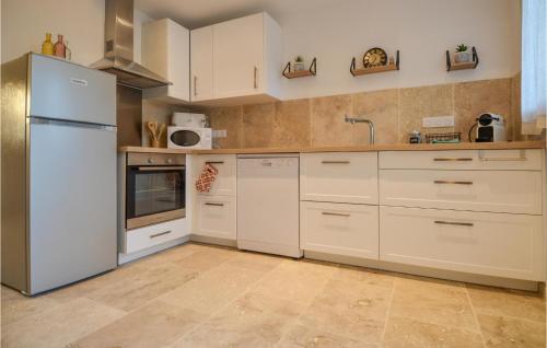  La cuisine est équipée de placards blancs et d'un réfrigérateur. dans l'établissement Ricard, à Arles