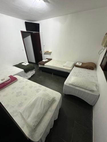 a room with three beds in a room at Pousada e Restaurante Dona Lu in Itaperuna