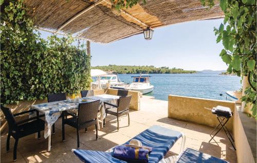 a patio with tables and chairs and a boat in the water at Apartment Banici Ii in Slano