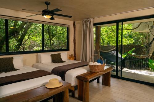 a bedroom with two beds and a large window at Sunset House in Tulum