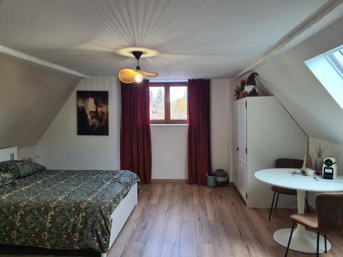 a bedroom with a bed and a table and a window at L'escale champêtre in Uhrwiller