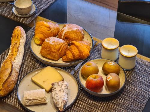 une table avec trois assiettes de viennoiseries, de pommes et de pain dans l'établissement L'escale champêtre, à Uhrwiller