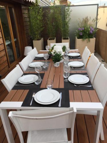 une table en bois avec des assiettes blanches et des verres dessus dans l'établissement Air conditioned apartment 78 m2, Terrace 50m2, à Paris