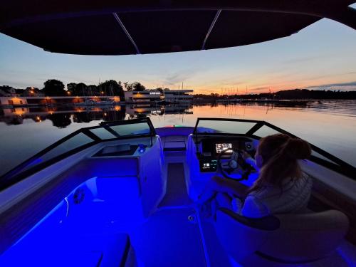 a woman driving a boat in a body of water at Marina Luna - widok na jezioro, parking podziemny, winda, Netflix, Max in Iława