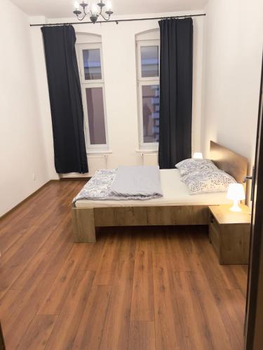a bedroom with a bed and a wooden floor at Apartament Plac Klasztorny in Legnica