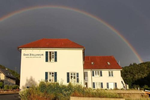 a rainbow over a white house with a building at In DE preiswert wohnen und in der CH gut verdienen in Klettgau