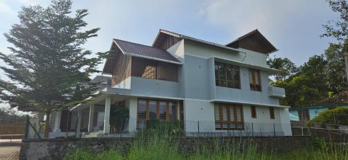 a white house with a tree in front of it at Grace villa in Piravam