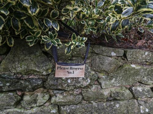 a sign on a stone wall with a plant at 1 Boarbank Farm in Grange Over Sands