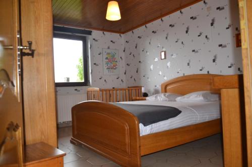 a bedroom with a wooden bed and a window at La Maison du Bonheur in Gouvy