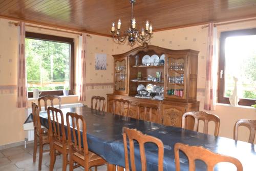 a dining room with a table and chairs and a chandelier at La Maison du Bonheur in Gouvy