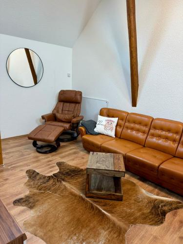 a living room with a brown leather couch and a chair at Ferienhaus Auszeit in Medebach