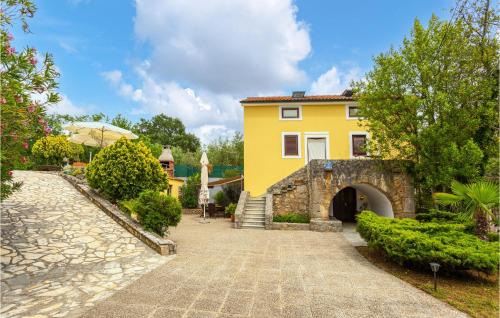 une maison jaune avec un chemin en pierre devant dans l'établissement Amazing Home In Malinska With Kitchen, à Malinska