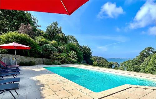 - une piscine avec un parasol rouge et des chaises dans l'établissement Amazing Home In Concarneau, à Concarneau