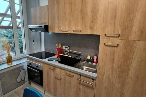 une cuisine avec des armoires en bois, un évier et une cuisinière dans l'établissement Suite Beaulieu 3 - 2 chambres cosy, à Angoulême