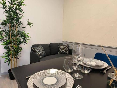 une table avec des assiettes, des verres et un canapé dans l'établissement Suite Beaulieu 3 - 2 chambres cosy, à Angoulême