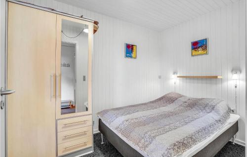 a bedroom with a bed and a cabinet with a mirror at Amazing Home In Rømø With Kitchen in Havneby