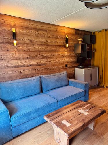 - un salon avec un canapé bleu et un mur en bois dans l'établissement Superbe studio de montagne, au pied des pistes de ski, classé 3 étoiles, à La Morte