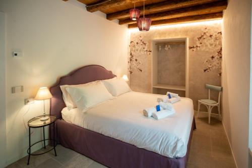 Le Cornici Home Suites - Apartments - Lake Idro في Ponte Caffaro: غرفة نوم مع سرير مع دبتين عليه