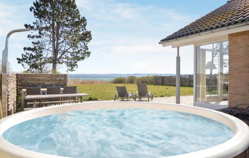 FemmøllerにあるHoliday Home Bogenshovedvejのホットタブ付きのパティオ(テーブル、椅子付)
