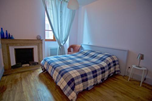 ポン・アン・ロワイヤンにあるChez Marieのベッドルーム1室(チェック入りの毛布、暖炉付)