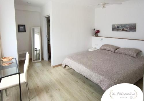 タコロンテにあるCasita El Peñoncitoの白いベッドルーム(ベッド1台、テーブル付)