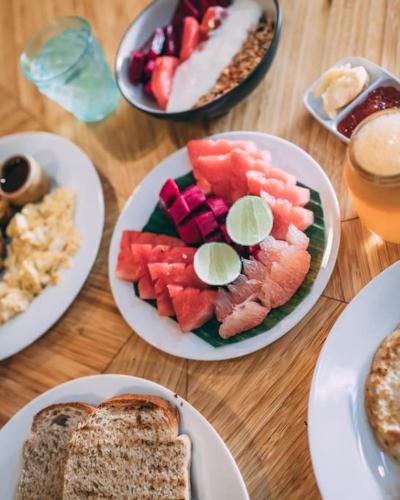 a wooden table with plates of food and bread at Aura House 2bds Eco Bamboo House, Pool, River View in Bringkit