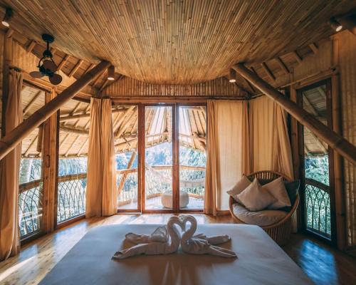 a bedroom with a bed with two hands on it at Aura House 2bds Eco Bamboo House, Pool, River View in Bringkit