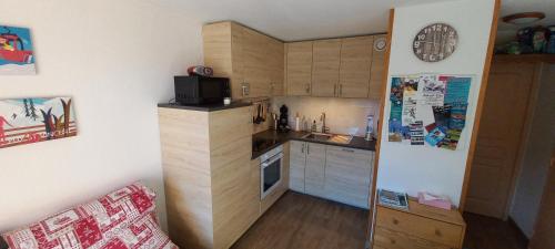 Elle comprend une petite cuisine avec des placards en bois et un réfrigérateur. dans l'établissement Appartement Puy Saint Vincent 1800 - 6 personnes, à Puy-Saint-Vincent