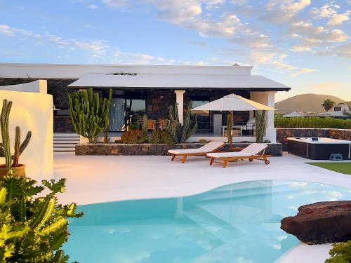 a villa with a swimming pool and a house at UNIQUE Homes Lajares - adults only in Lajares