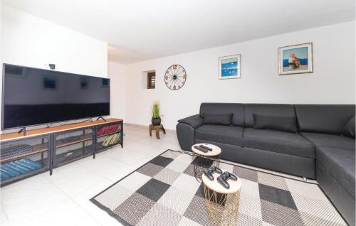 a living room with a black couch and a flat screen tv at Two-Bedroom Holiday Home In Trilj in Trilj