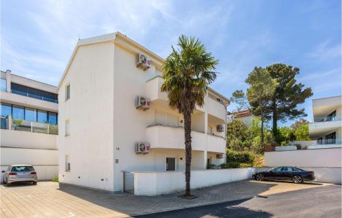 a white building with a palm tree in a parking lot at Lovely Apartment In Malinska With Wifi in Malinska