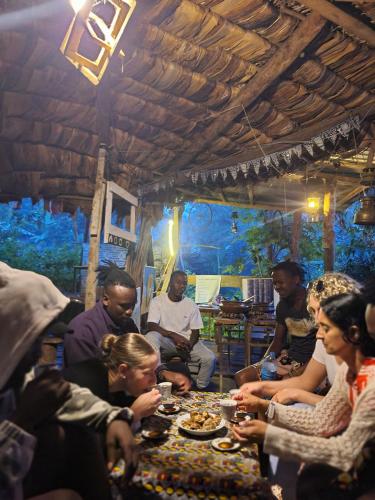 een groep mensen die rond een tafel zitten te eten bij Aroma Home - Eco-Cabins on a Coffee Farm in Arusha