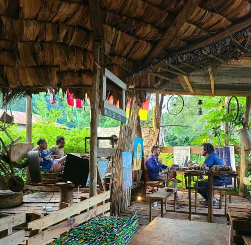 een groep mensen die aan tafels in een restaurant zitten bij Aroma Home - Eco-Cabins on a Coffee Farm in Arusha
