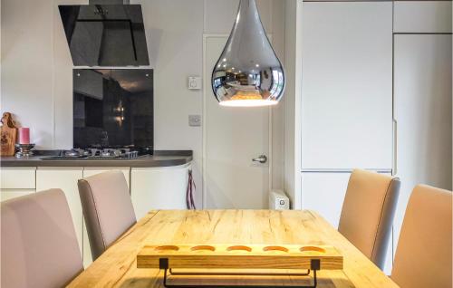 a kitchen with a wooden table with chairs and a light at 2 Bedroom Amazing Home In Heinkenszand in Heinkensand