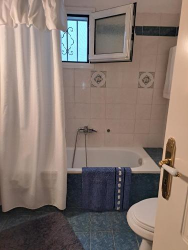 a bathroom with a tub and a toilet and a shower curtain at Σπιτι μου σπιτακι μου in Pyrgetós