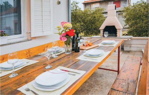 einen Holztisch mit Tellern, Weingläsern und Blumen in der Unterkunft Apartment Stablinec Iv,br, Cr in Vodice