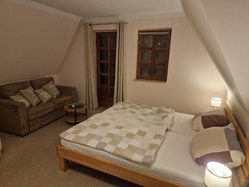 a small bedroom with a bed and a couch at Gasthaus Fontane GmbH in Wildau