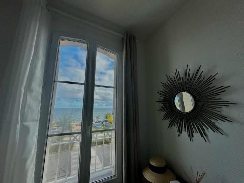 a mirror on a wall in a room with a window at Bel Horizon, charmant appt avec balcon vue mer in Luc-sur-Mer