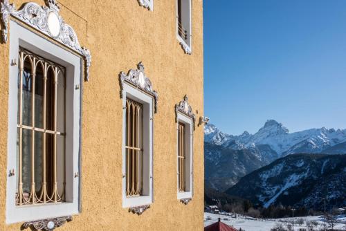 three windows on a building with mountains in the background at Càdor Hotel in Valle di Cadore