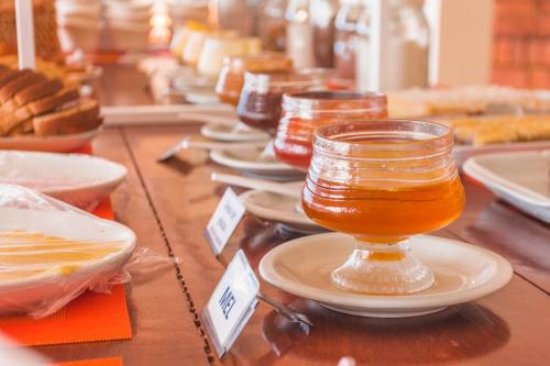 a glass jar of honey on a table with dishes at Ferrujão Pousada e Restaurante in Garopaba