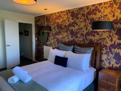 a bedroom with a large white bed and floral wallpaper at Incredible mountain & sea views in Mapua