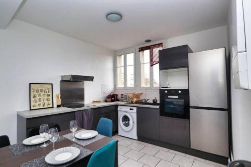 une cuisine avec une table, des chaises et un réfrigérateur dans l'établissement Suite Houmeau 2-Ecran Cinéma, à Angoulême