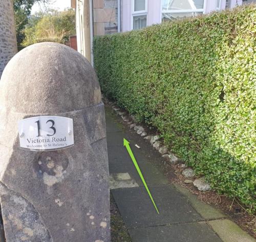 a rock with a sign on it next to a hedge at Welcome to St Helena Dunoon, a traditional villa in Dunoon