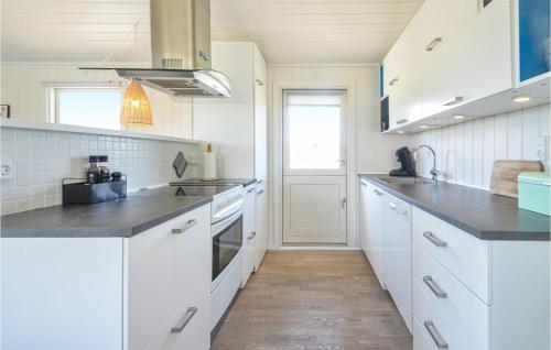 a kitchen with white cabinets and black counter tops at Holiday Home Johnsvej Thisted V in Klitmøller