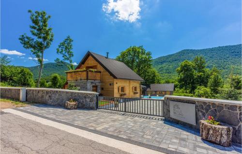 a log house with a fence and a stone wall at Cozy Home In Buzim With Sauna in Bužim