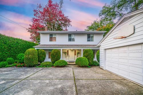 a white house with bushes and a garage at Garden Hotel 3-bedroom house for whole book in Richmond