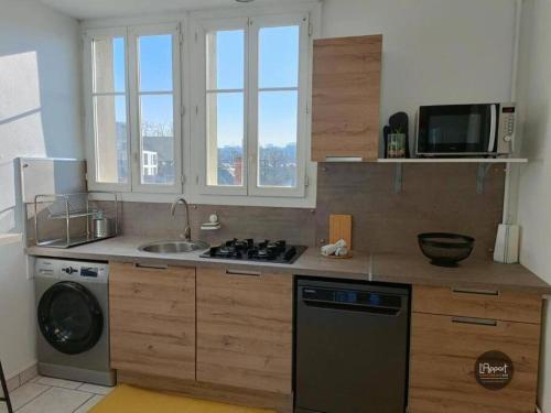 une cuisine avec une cuisinière, un évier et un micro-ondes dans l'établissement Suite Houmeau 3- Gare Pôle Image, à Angoulême