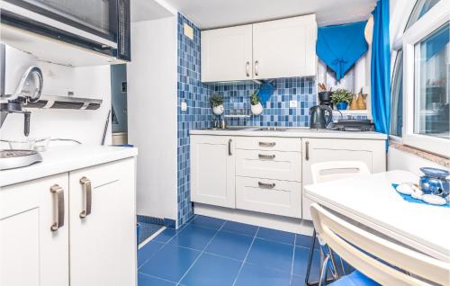 a kitchen with white cabinets and blue tiles at Cozy Home In Miholascica With Wifi in Miholašćica
