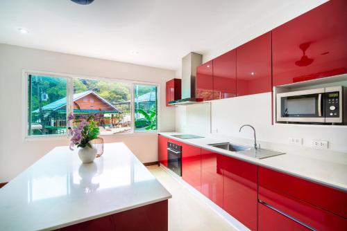 a kitchen with red cabinets and a white counter top at patong villa3 四卧海景泳池别墅 近班赞海鲜市场 中英泰三语服务 in Patong Beach